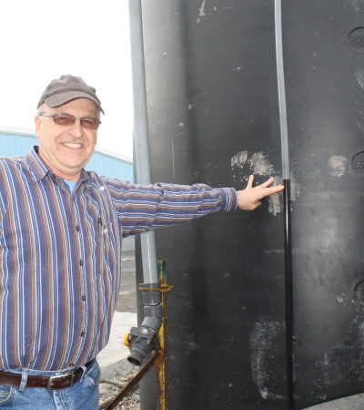 Madawaska Public Works Director Yves Lizotte points out the level of molasses in an outdoor tank, Thursday, March 1, at the department's garage. Public Works is trying a new system that uses molasses to help its sand/salt mixture adhere better to winter roads. (Don Eno | SJVT/FhF)